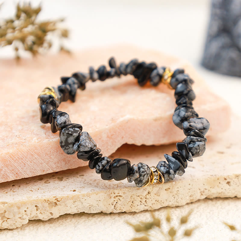 Schwarzes Edelsteinarmband mit goldenen Akzenten auf hellem Steinuntergrund, Schmuckaccessoire.