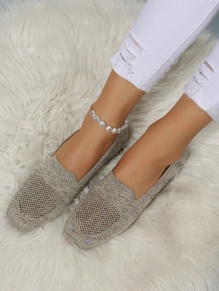 Beige-grå mesh slip-on sko på model med hvide flossede jeans og perleanklet, på hvidt fluffy tæppe. 20