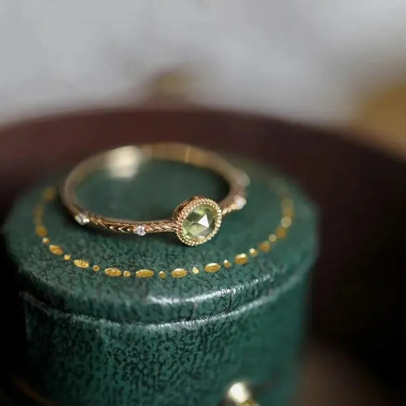 Goldring mit grünem Edelstein auf grünem Schmuckkästchen, elegantes Schmuckdesign.