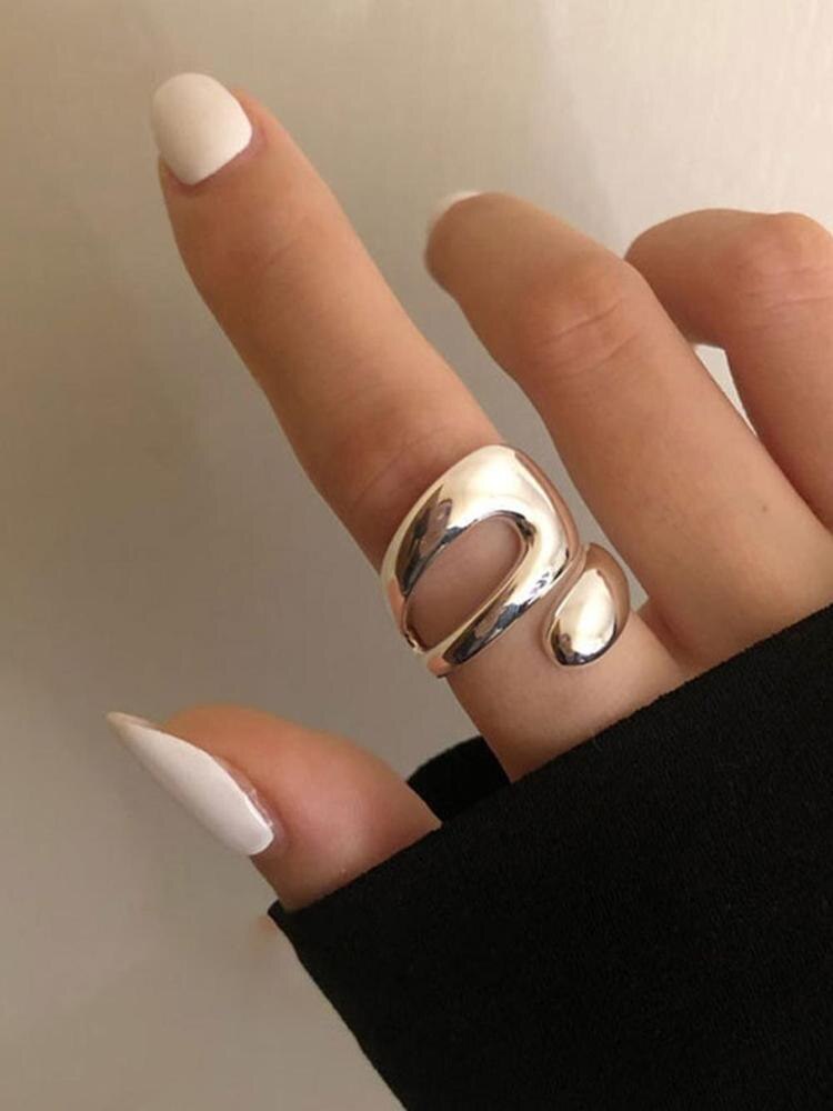 Silberner Statement-Ring, modern, glänzend, an Finger getragen, minimalistisches Design.