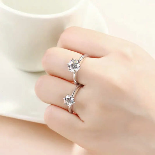 Zwei silberne Verlobungsringe mit Diamanten auf Hand, elegantes Schmuckdesign.