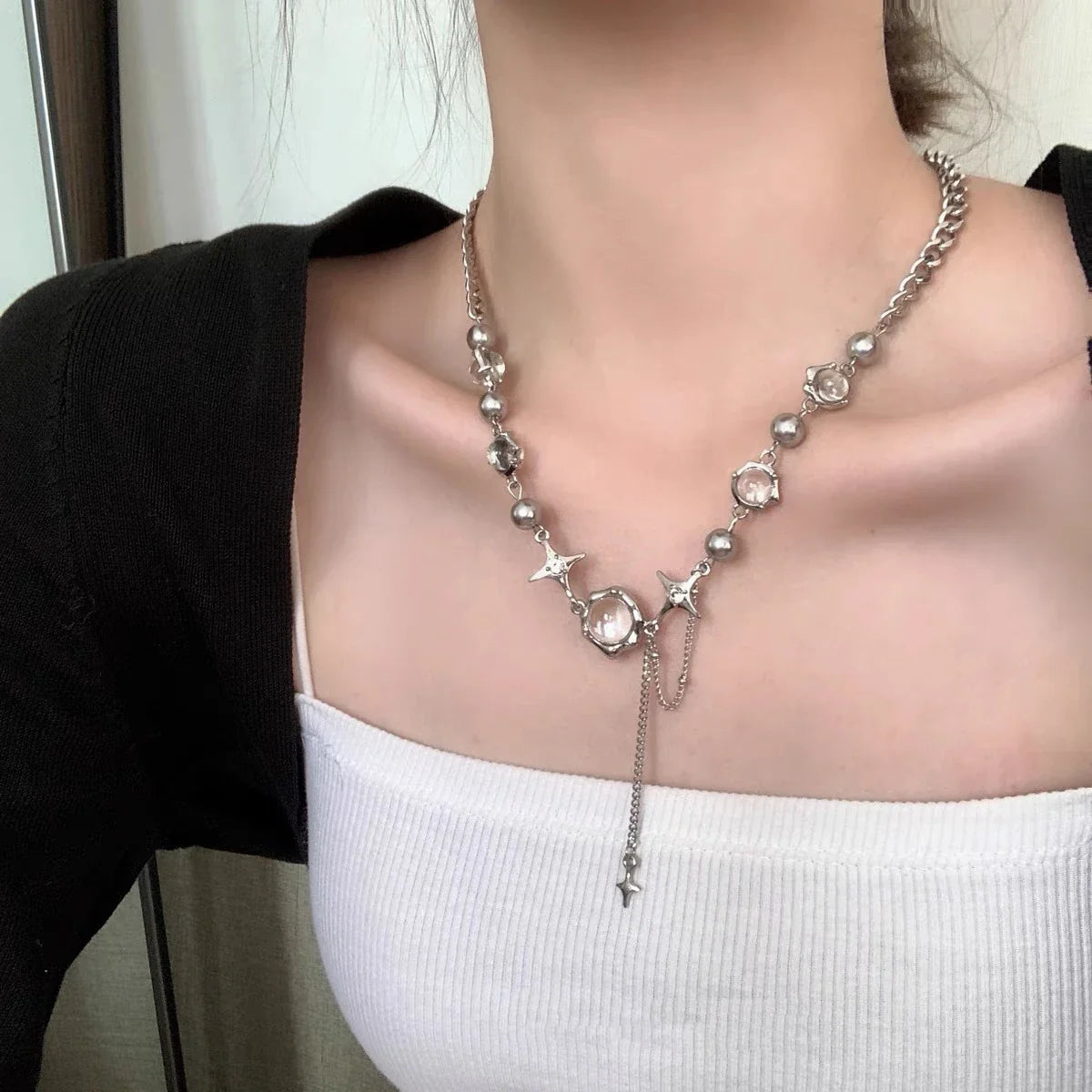 Frau mit silberner Halskette, Perlen und Anhängern, modisches Accessoire, Nahaufnahme.