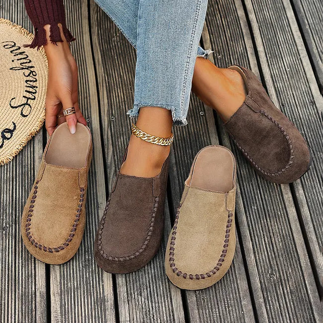 Tre par slip-ons i lysebrun og mørkebrun på en træterrasse, set ovenfra med modellens ben imellem. 7