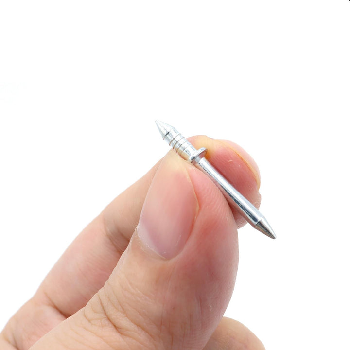 Nærbillede af ét dobbelthoved søm holdt mellem tommel- og pegefinger, med den rillede ende og den glatte spids. 4