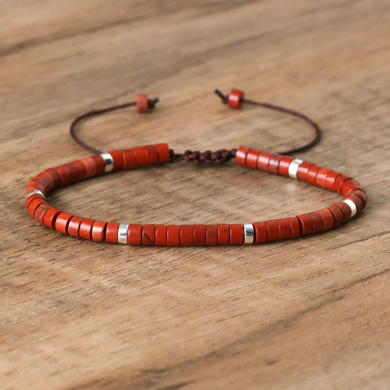 Rotes Perlenarmband aus Holz mit silbernen Akzenten auf Holztisch, verstellbar, handgefertigt.