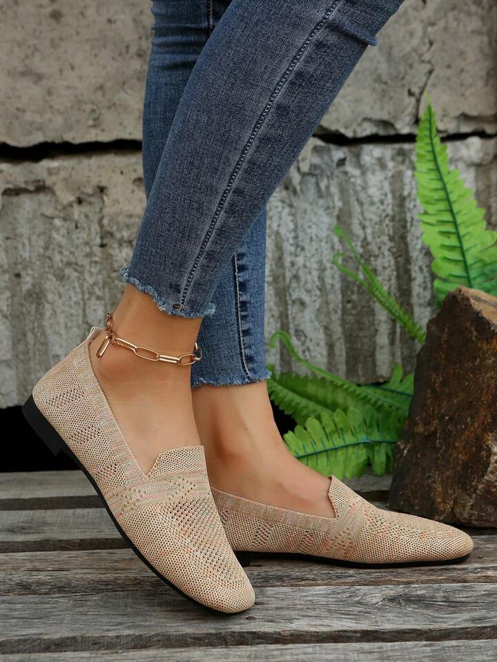 Beige mesh slip-on sko set fra siden på model i jeans med guldkæde om anklen, ved bregner og sten. 4