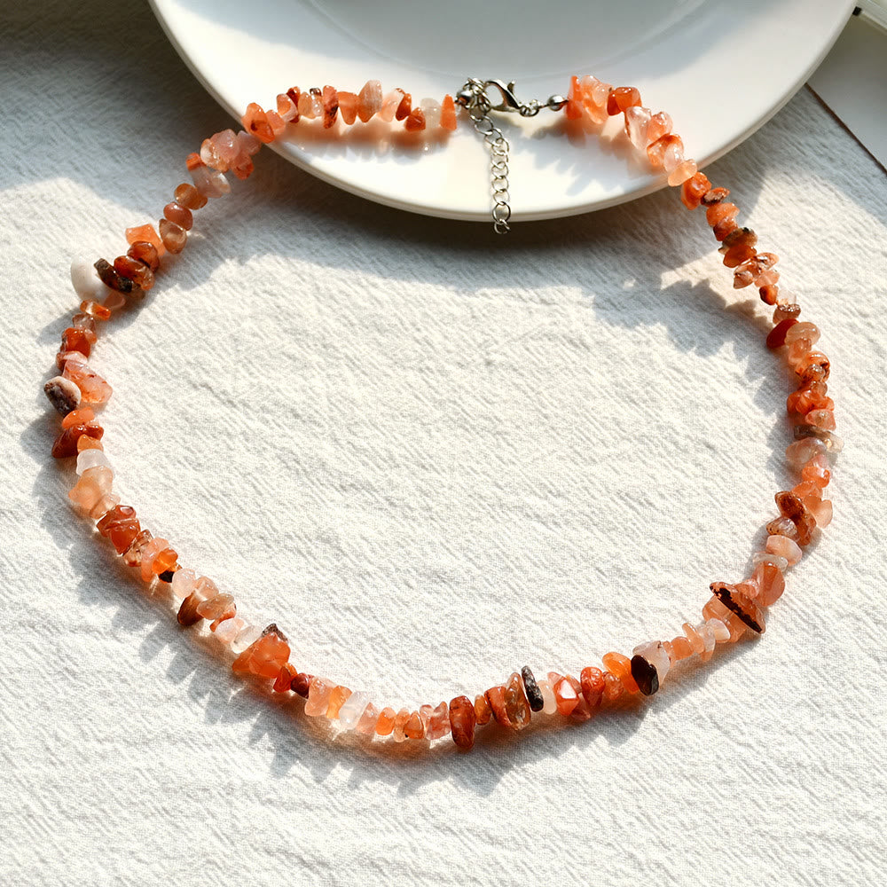 Halskette aus orangefarbenen Edelsteinen auf weißem Hintergrund, handgefertigter Schmuck.