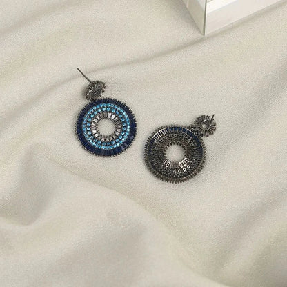 Blaue und silberne Ohrringe auf beigem Stoff, handgefertigter Schmuck, modisches Accessoire.