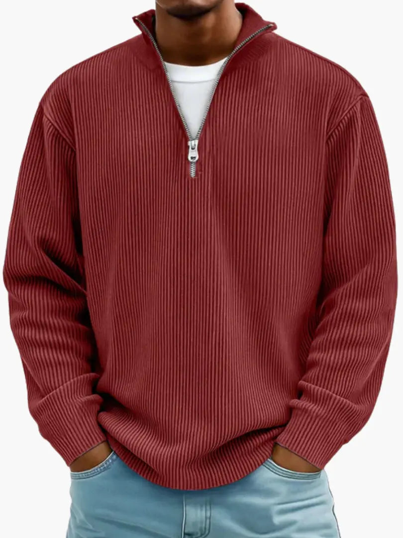 Model i rødbrun ribstrikket trøje med kvart lynlås og høj krave, hvid T-shirt under og lyseblå jeans. 10