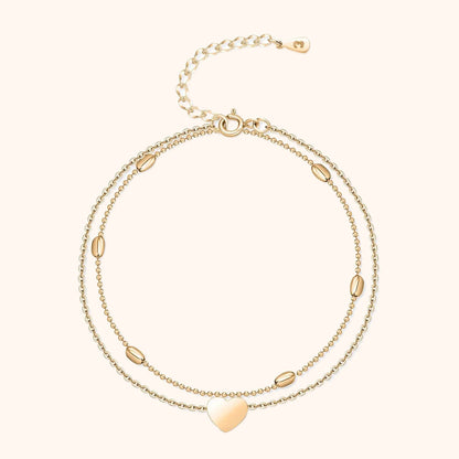 Zweireihiges goldfarbenes Armband mit Herzanhänger und ovalen Details, verstellbar.