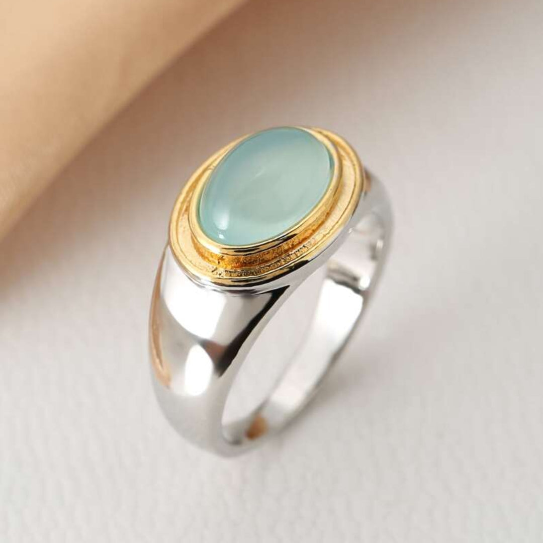 Silberring mit ovalem, hellblauem Edelstein und goldener Fassung, eleganter Schmuck.