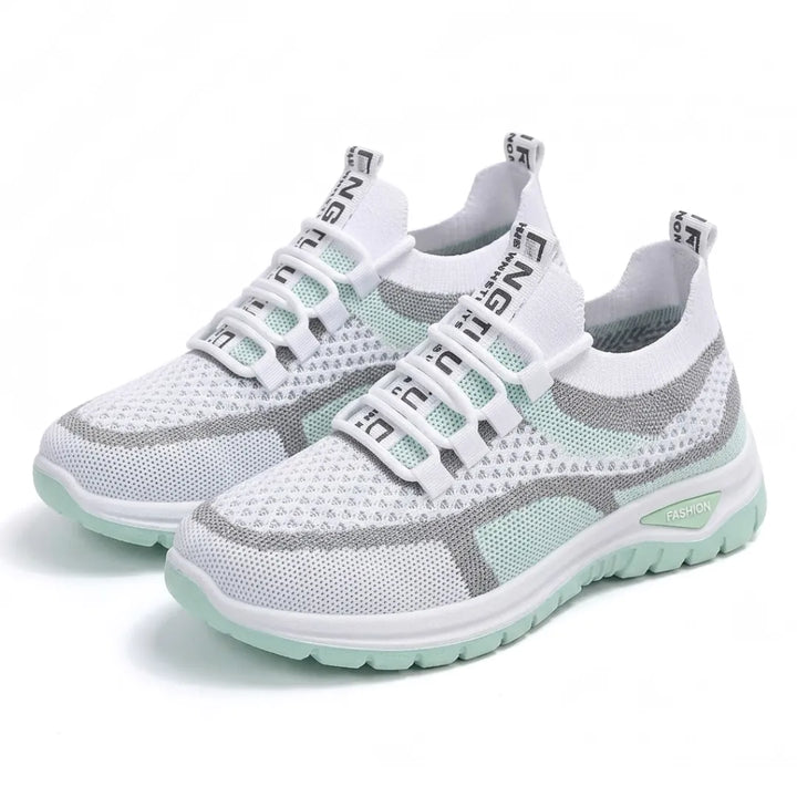 Et par hvide sneakers med mintgrøn sål og grå striber set på skrå forfra på hvid baggrund. 16