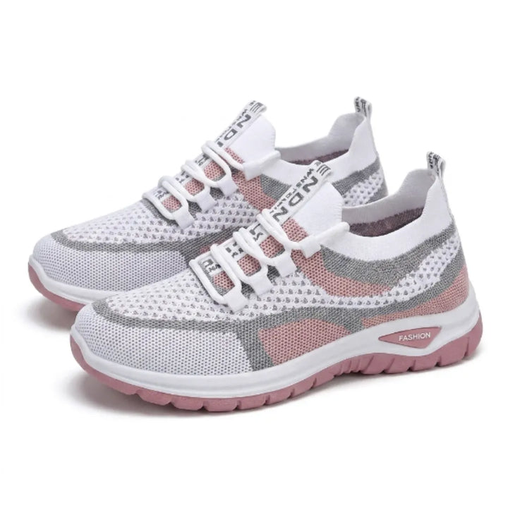 Et par hvide sneakers med grå og lyserøde felter i åndbart mesh, snørebånd og lyserød tyk såle, set skråt forfra. 25