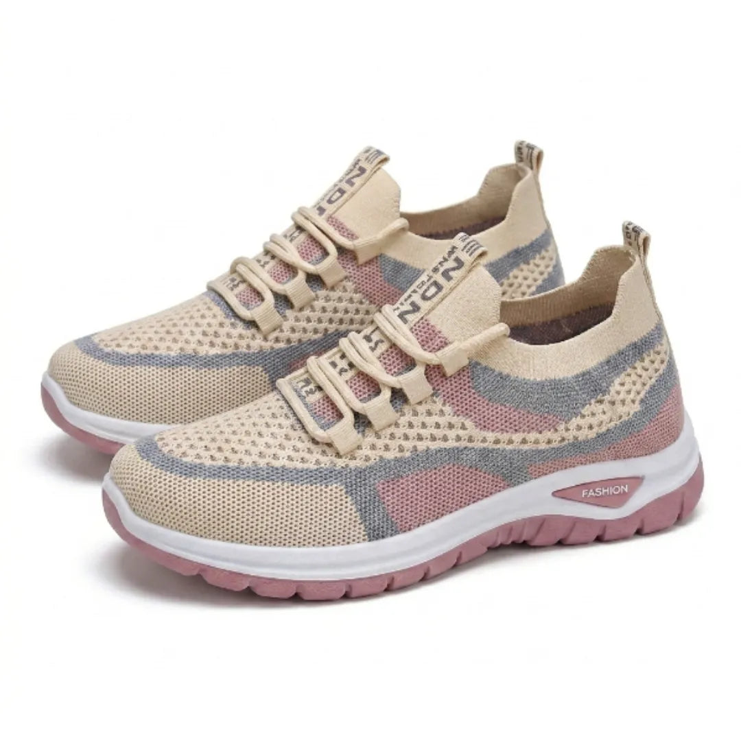 Et par beige sneakers med blå og lyserøde felter i åndbart mesh, snørebånd og lyserød tyk såle, set skråt forfra. 34