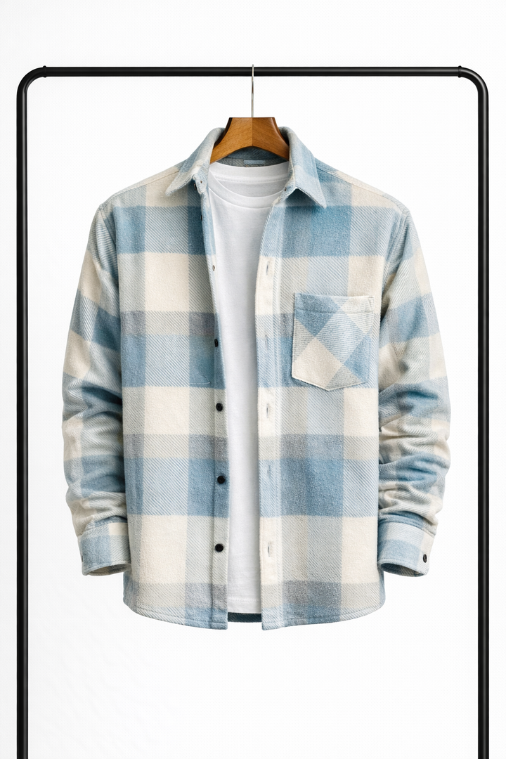 Ternet overshirt i lyseblå og creme set forfra på bøjle, åben over en hvid t-shirt, med brystlomme og sorte trykknapper. 1