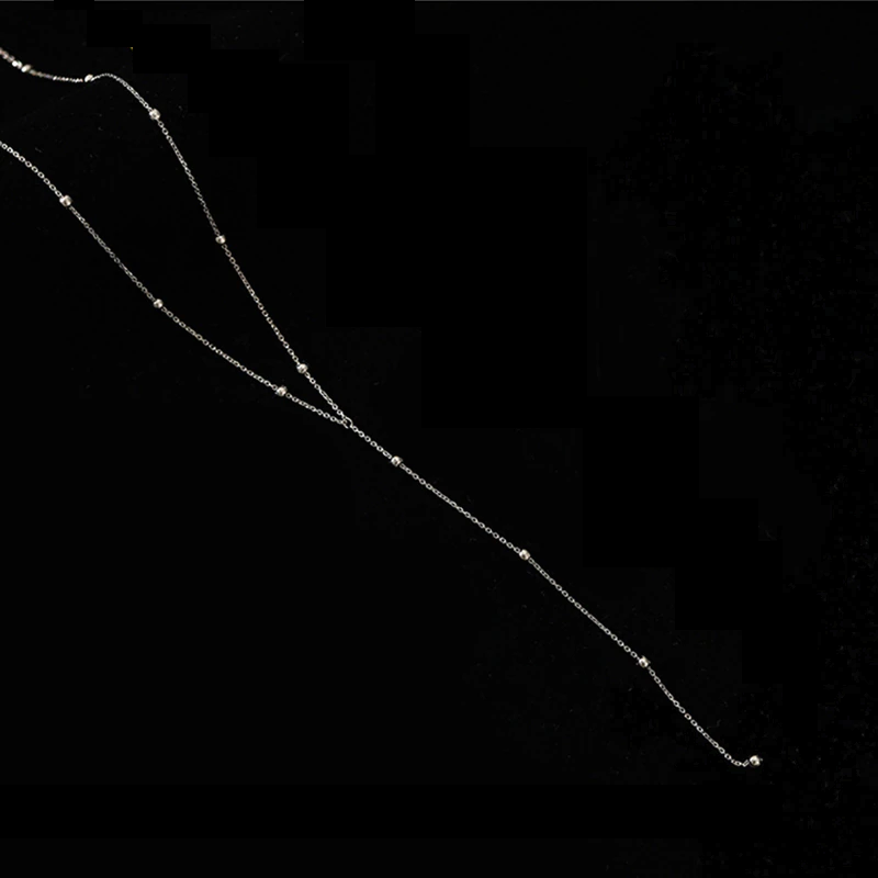 Silberne Halskette mit Perlen, elegantes Schmuckstück, minimalistisches Design auf schwarzem Hintergrund.