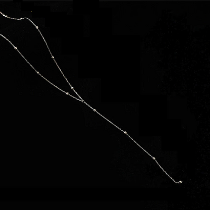 Silberne Halskette mit Perlen, elegantes Schmuckstück, minimalistisches Design auf schwarzem Hintergrund.
