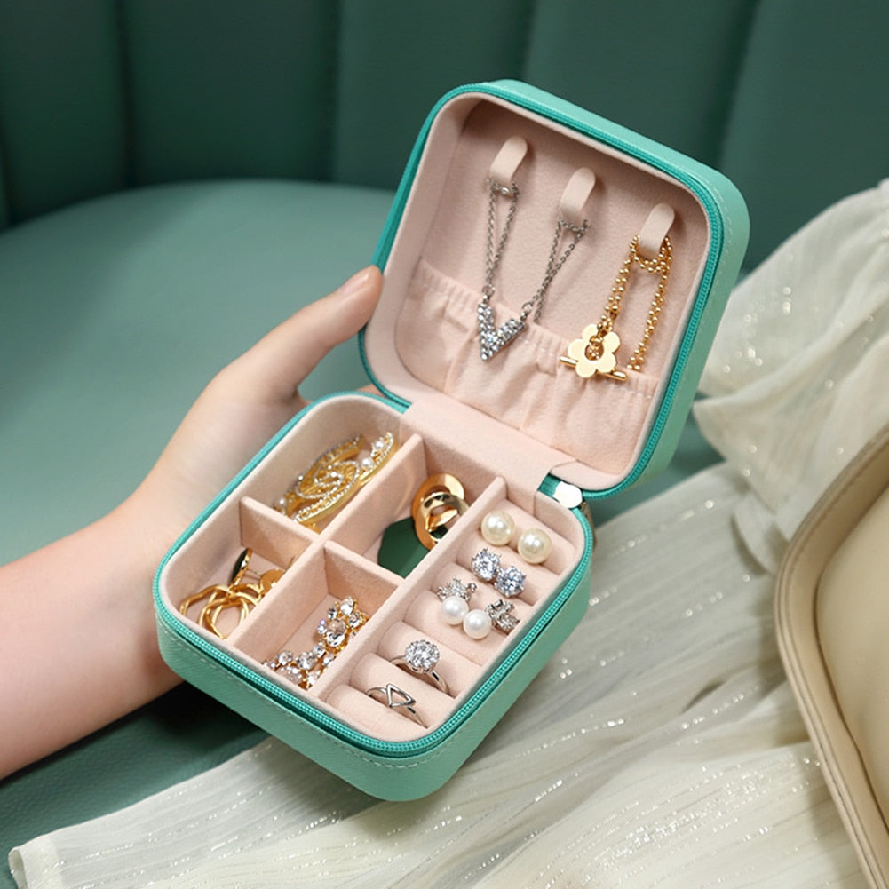 Türkisfarbene Schmuckbox mit Ringen, Ohrringen und Halsketten, ideal für Reisen und Aufbewahrung.