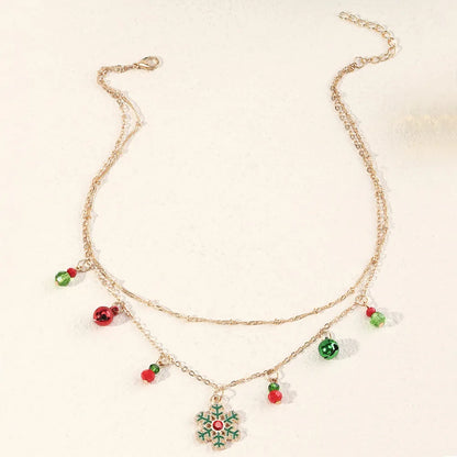 Goldene Halskette mit Weihnachtsanhänger, Schneeflocke, rote und grüne Perlen, festlicher Schmuck.