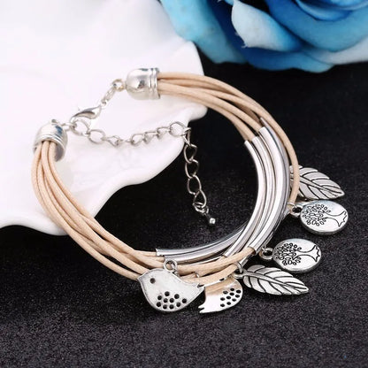 Beiges Lederarmband mit silbernen Anhängern, Blatt- und Vogelmotiv, Damenmode-Schmuck.