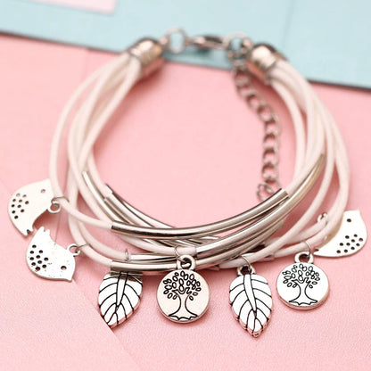 Mehrlagiges Armband mit weißen Lederbändern, silbernen Baum- und Blattanhängern, Damenmode.