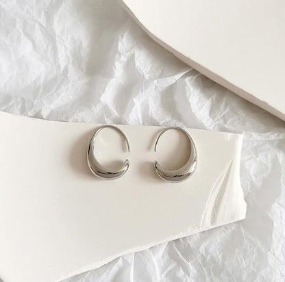 Silberne Creolen Ohrringe auf weißem Hintergrund, minimalistisches Schmuckdesign.