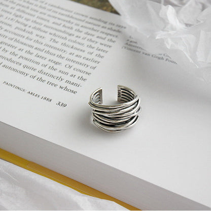 Silberner, verstellbarer Ring auf Buchseite, modernes Design, Schmuckaccessoire.