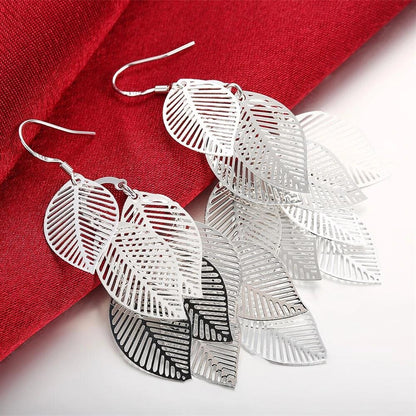 Silberne Blatt-Ohrringe, filigranes Design, modisch, Damen-Schmuck, auf rotem Stoff.