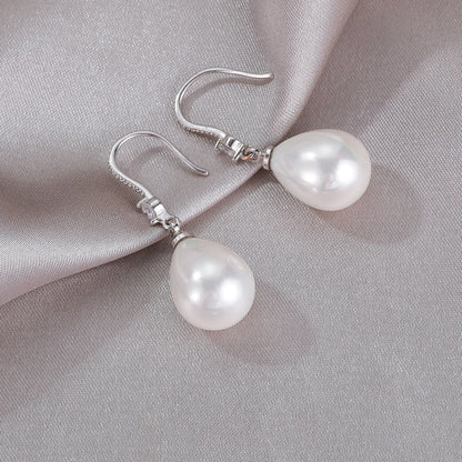 Silberne Ohrringe mit weißen Perlen, elegantes Schmuckdesign auf grauem Stoff.