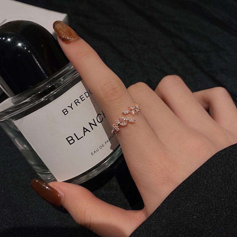 Damenring Roségold mit Kristallen, elegantes Design, neben Byredo Blanche Parfümflasche.