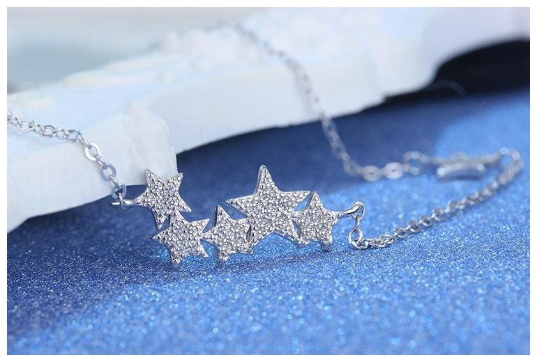 Silberne Stern-Halskette mit Strasssteinen auf blauem Hintergrund, eleganter Schmuck.