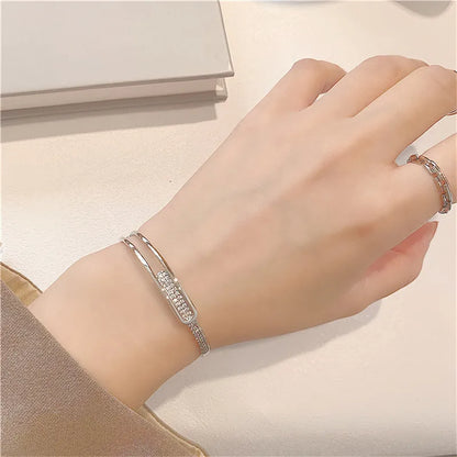 Silbernes Armband mit Strasssteinen auf Handgelenk, elegantes Schmuckdesign, Damenaccessoire.