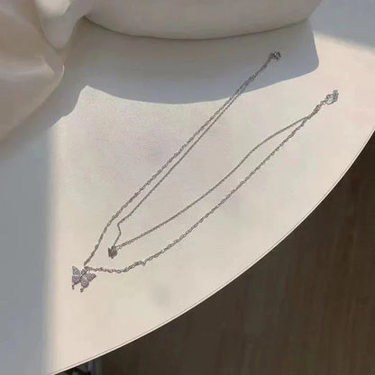Silberne Schmetterlingskette auf weißem Tisch, eleganter Schmuck, modisches Accessoire.