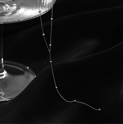 Silberne Halskette mit feinen Perlen auf schwarzem Hintergrund, eleganter Schmuck für Damen.