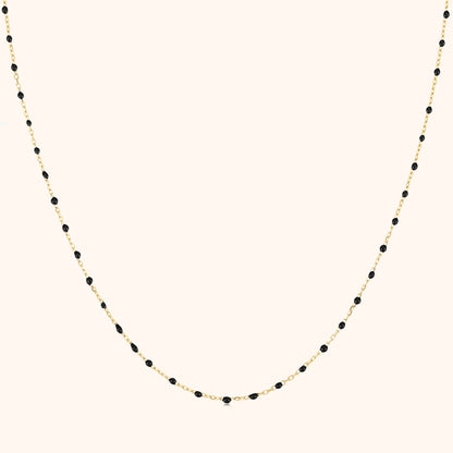 Goldene Halskette mit schwarzen Perlen, elegantes Schmuckdesign, Damenaccessoire.