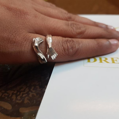 Silberner Ring in Handform auf Finger, einzigartiges Schmuckdesign, modischer Statement-Ring.