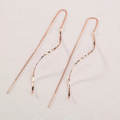 Roségoldene, lange Ohrringe mit geschwungenem Design, filigrane Kette, eleganter Schmuck.