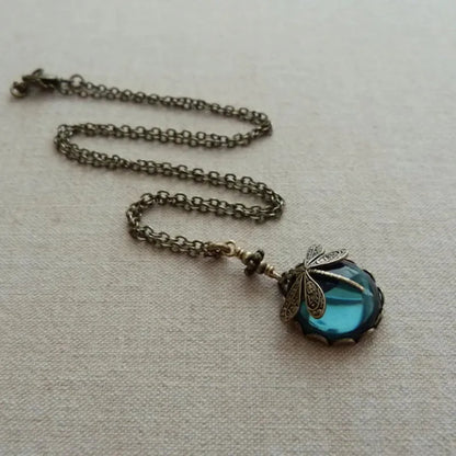 Antike Halskette mit blauem Glasanhänger und Libellenmotiv, Vintage-Schmuck, Metallkette.