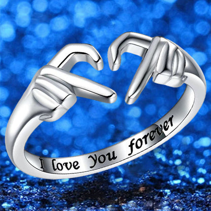 Silberring mit Handzeichen-Design, "I love you forever" Gravur, vor blauem Hintergrund.