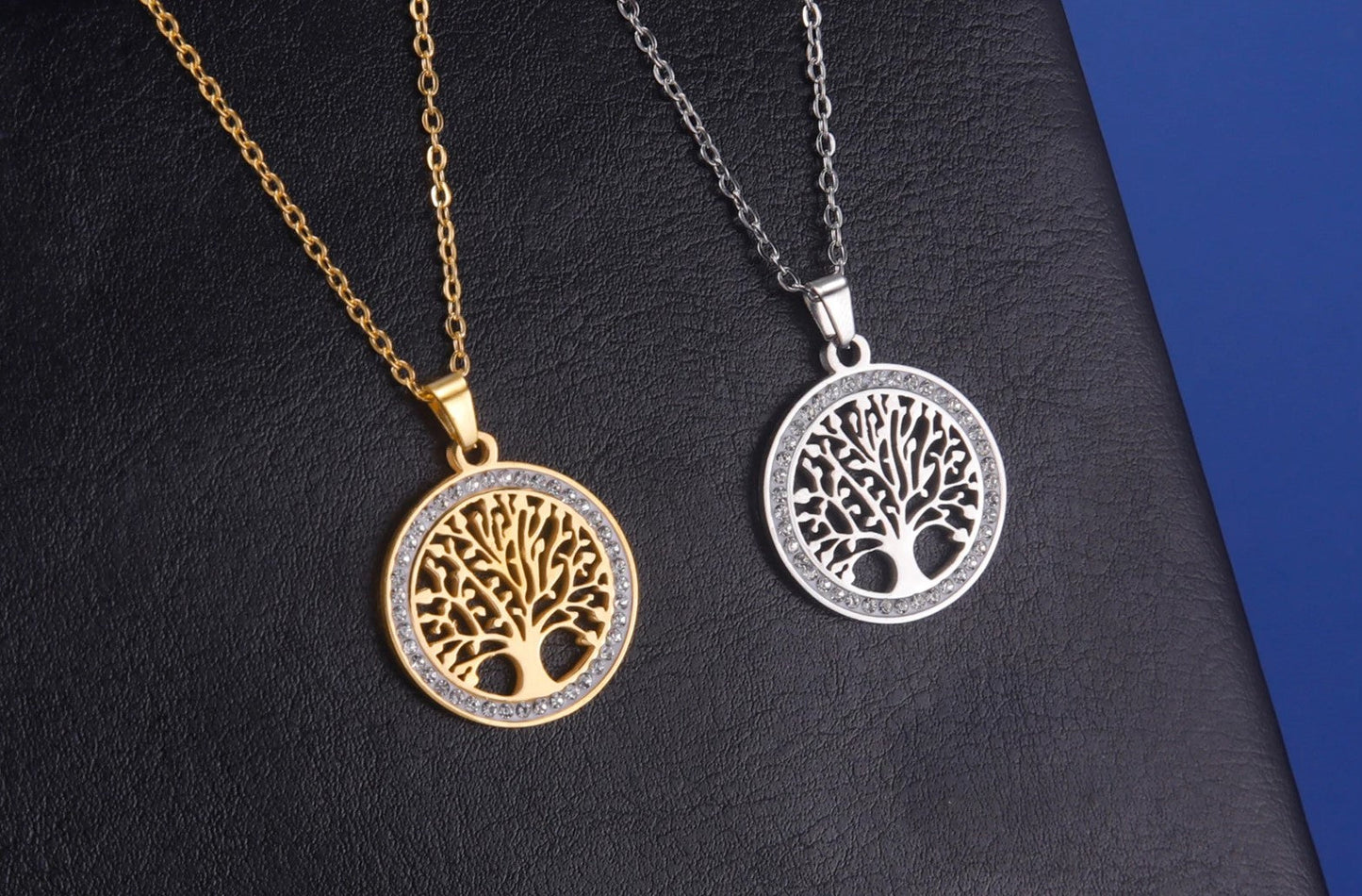 Zwei Lebensbaum-Anhänger, gold und silber, auf schwarzem Hintergrund, Schmuck, Halskette.