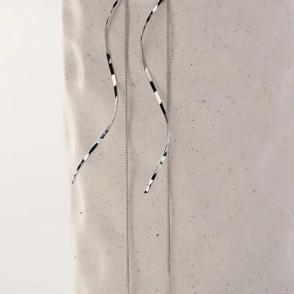 Silberne, lange Ohrringe mit schwarz-weißen Streifen auf hellem Hintergrund, minimalistisches Design.