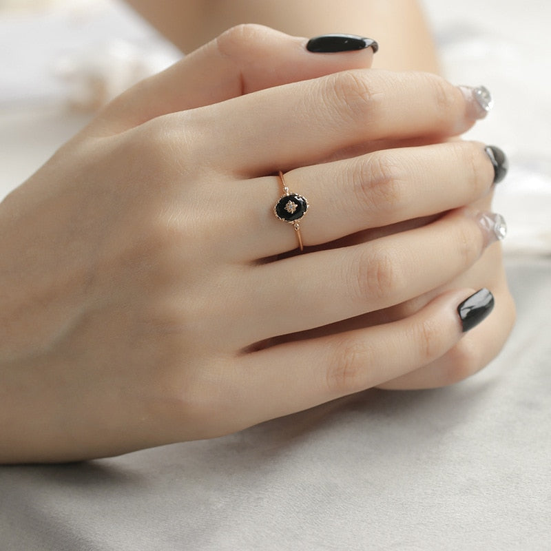 Damenhand mit schwarzem Diamantring, Roségold, elegantes Schmuckdesign.