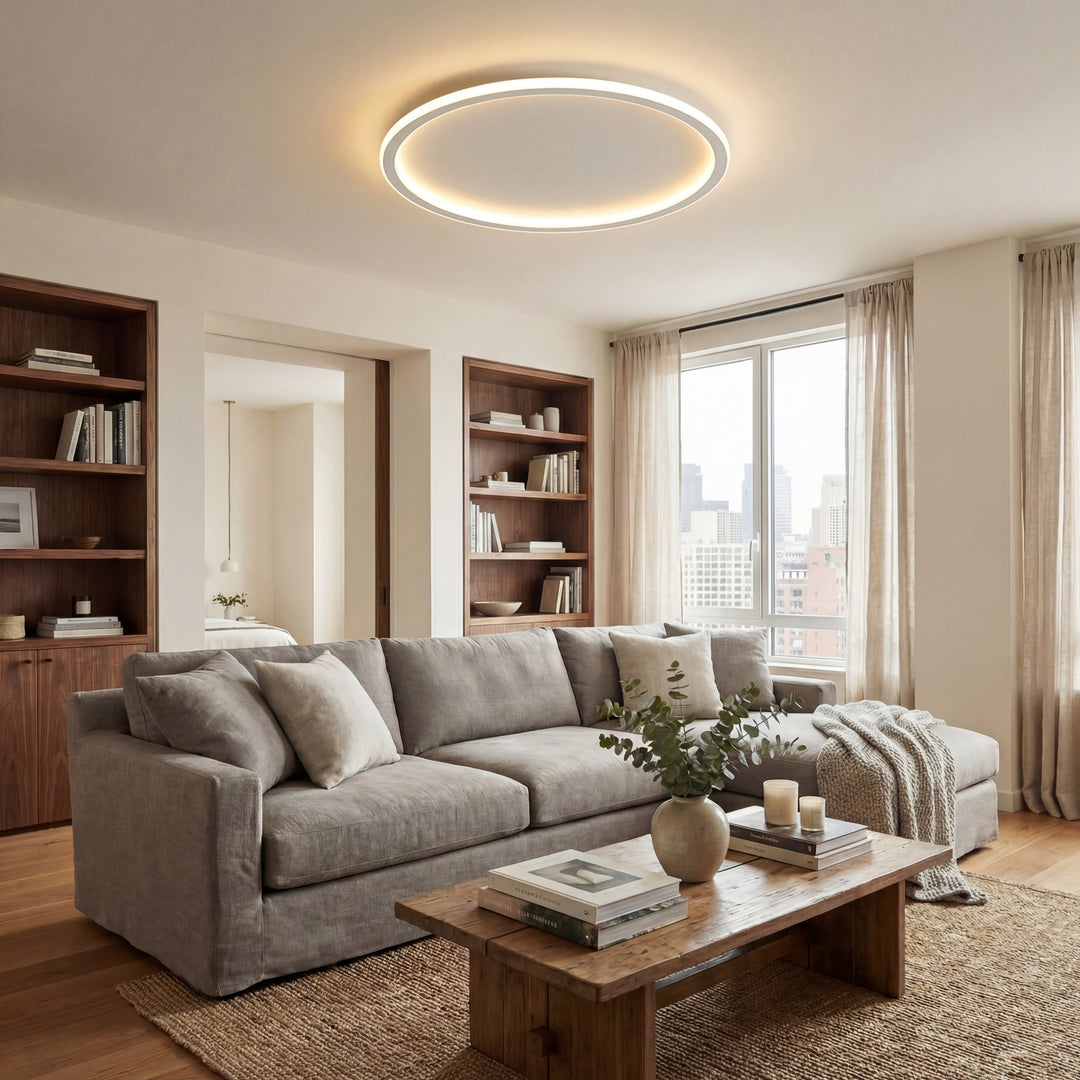 Rund LED-lampe i loftet i en stue med grå sofa, reoler i træ og sofabord. 5