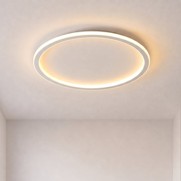 Tændt rund loftslampe med lysende ring og hvid ramme på et loft i et tomt rum med lyse vægge. 1