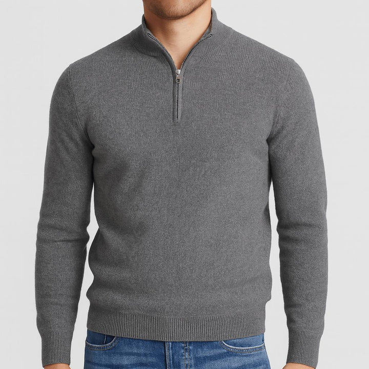 Model i grå strikbluse med lynlås i halsen og ribkanter, kombineret med blå jeans, set forfra. 4