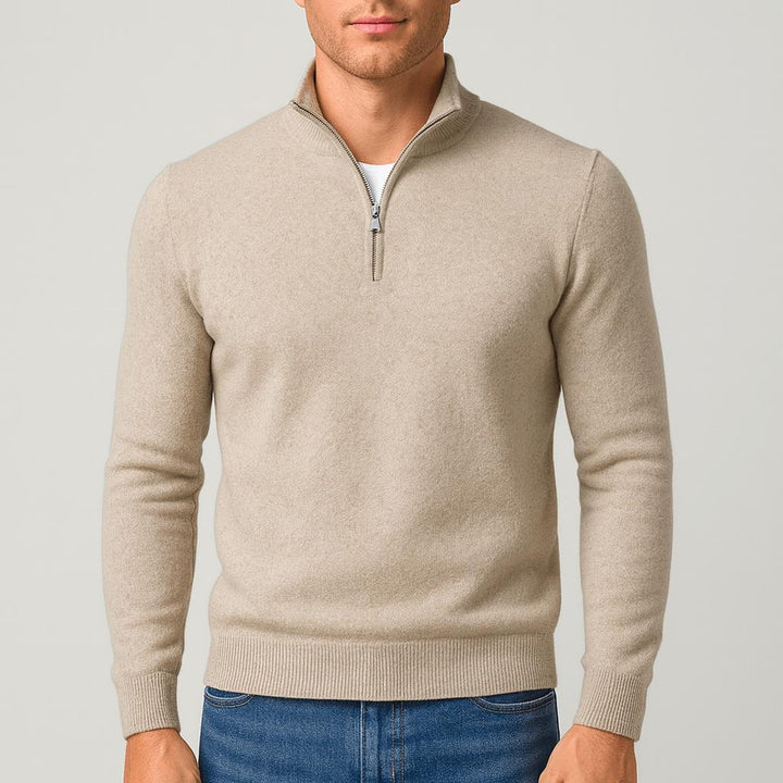 Model i beige strikbluse med høj krave og kort lynlås, ribkanter ved ærmer og linning, blå jeans. 9