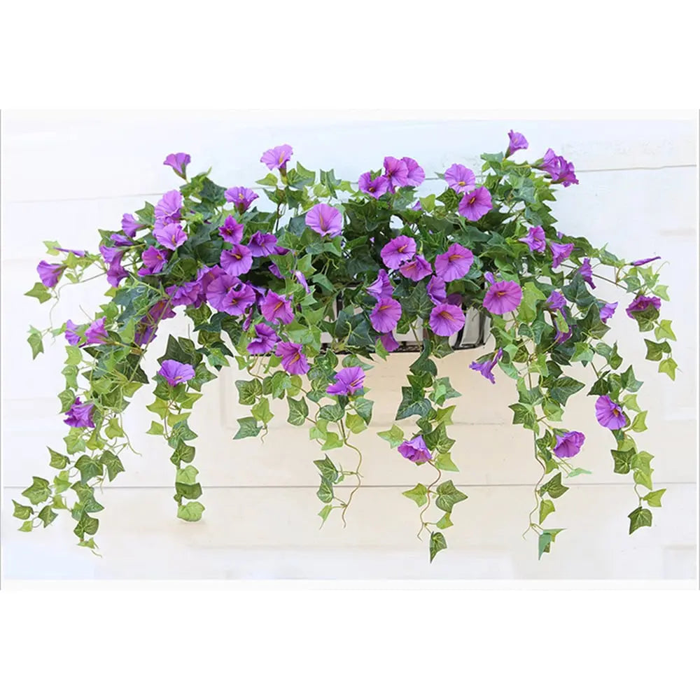 Violette kunstige blomster med hængende grønne ranker i en vindueskasse monteret på en hvid væg. 6