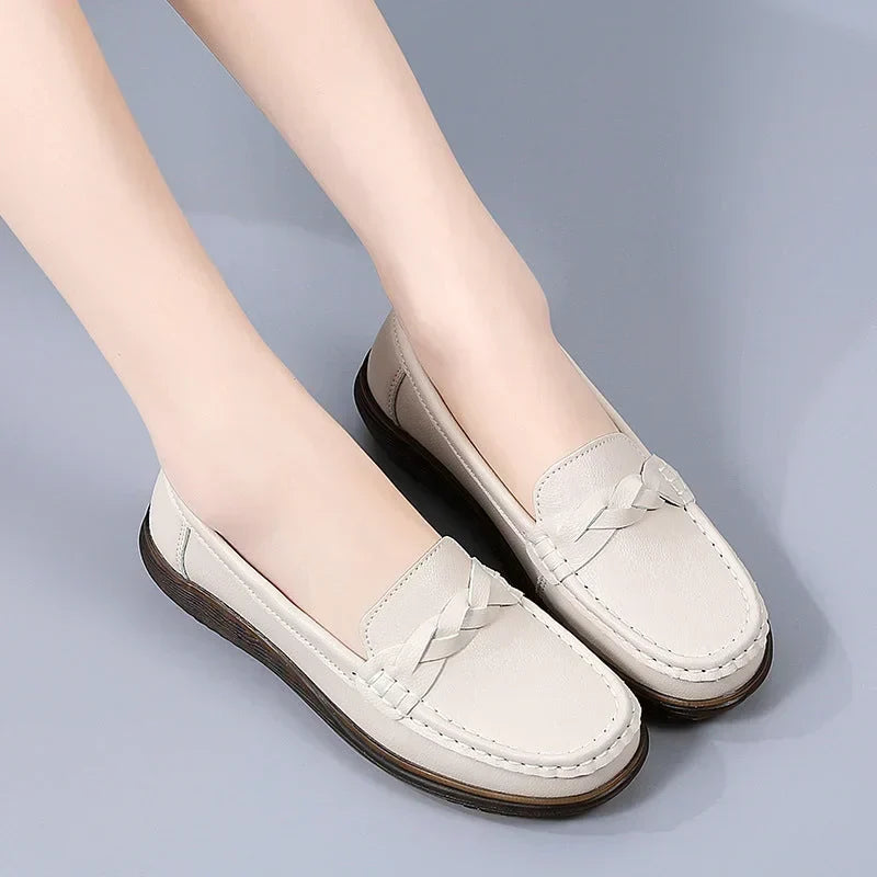 Beige loafers båret af model mod lysegrå baggrund, set skråt forfra med flettet pynt og mørk, tyk gummisål. 9