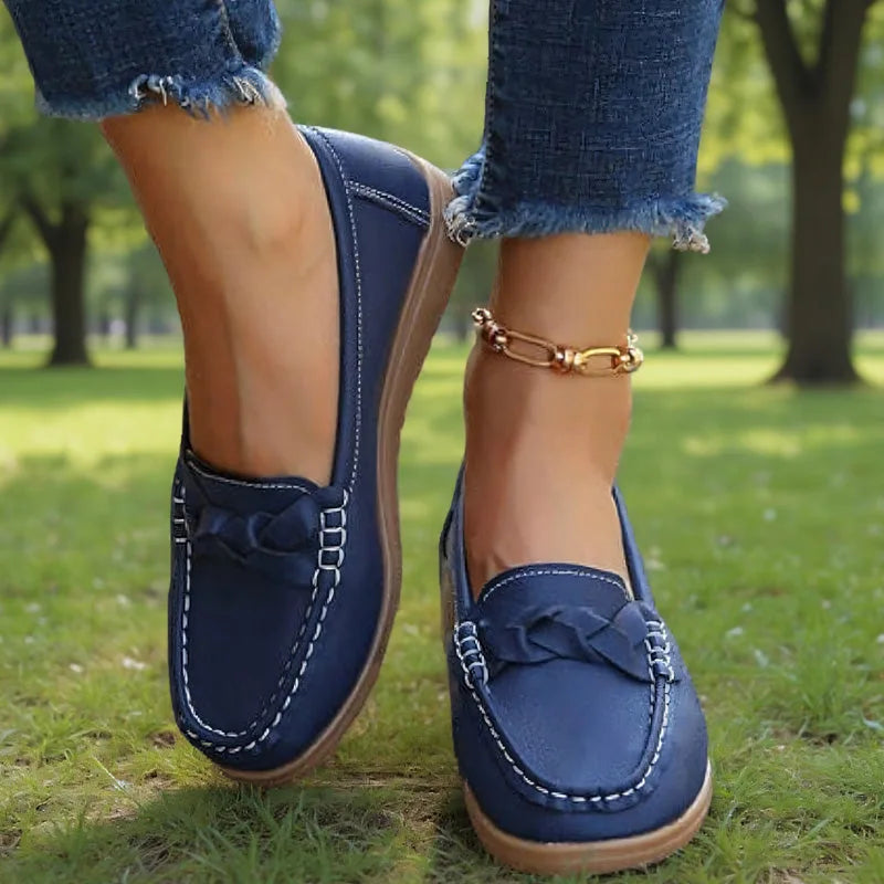 Mørkeblå loafers båret af model i en park, set forfra med flettet pynt og hvid kontrastsyning. 6