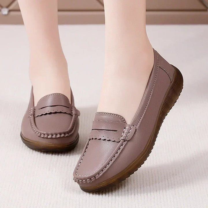 Gammelrosa loafers båret af model på et lyst gulvtæppe, med bælte-pynt med bølget kant og synlig syning ved tåen. 13